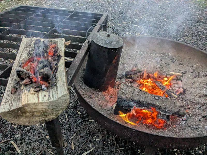 Feuerschale mit glühender Glut und schwarzem Wasserkessel